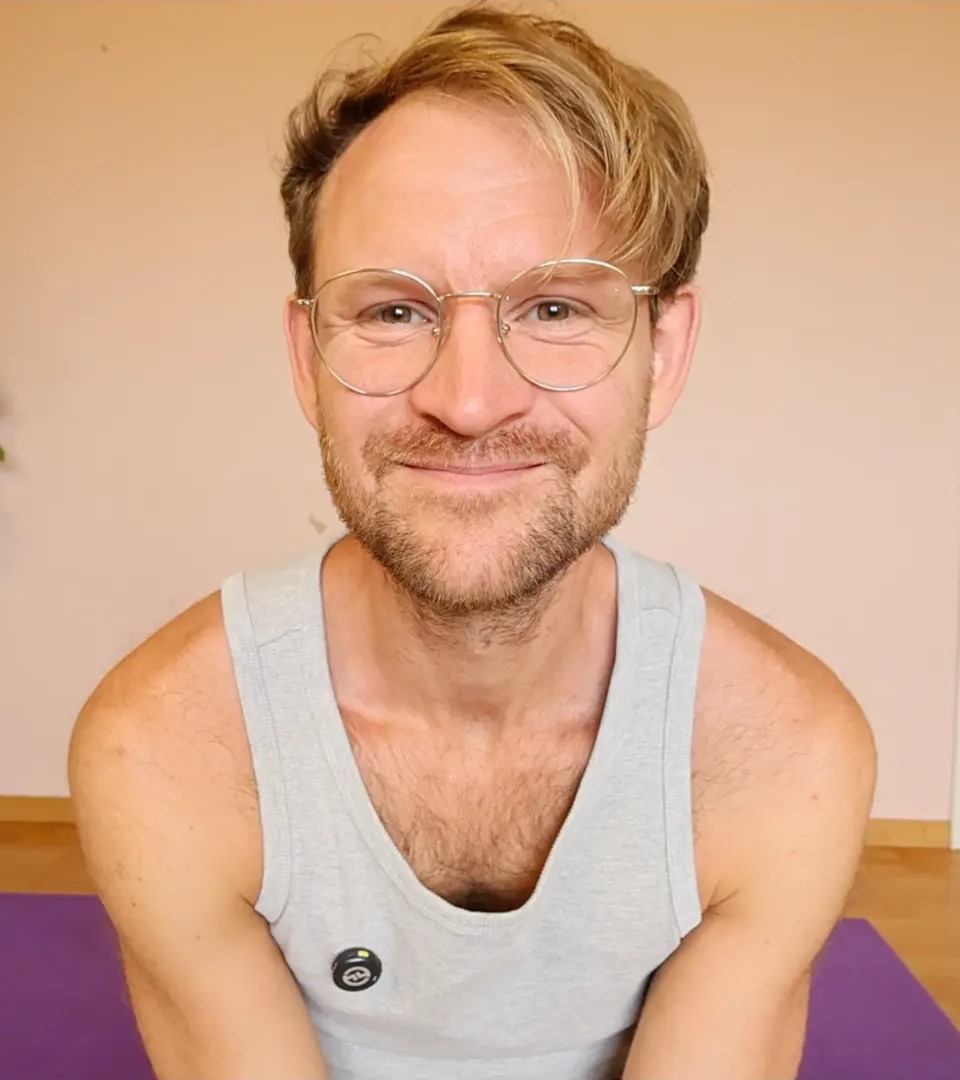 Jona Kimhag Lövheim ler på en lila yogamatta i ett rum med ljus trägolv